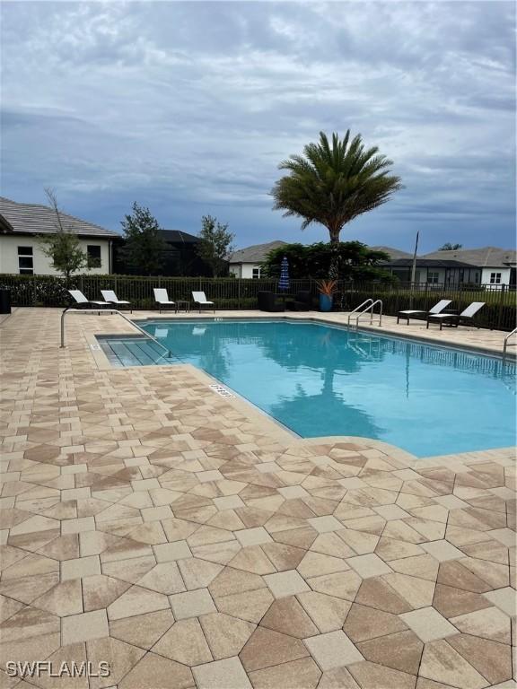 pool with a patio area and fence