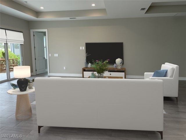 living room with recessed lighting, a raised ceiling, visible vents, and baseboards