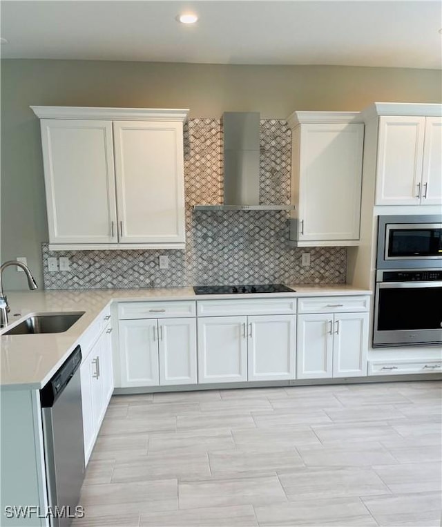 kitchen with stainless steel appliances, light countertops, backsplash, a sink, and wall chimney exhaust hood