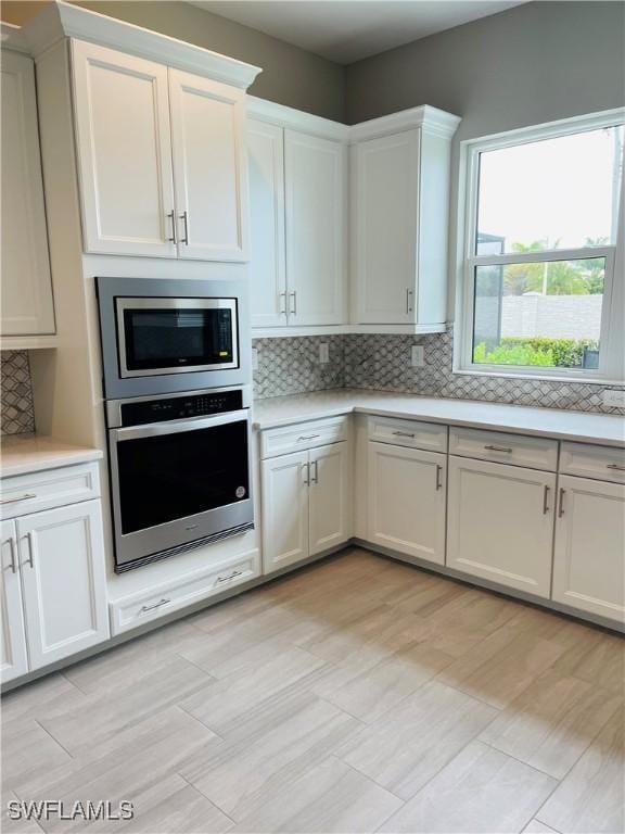 3608 Sapphire Cove Cir, Naples, FL 34114 - kitchen featuring white cabinets, tasteful backsplash, stainless steel appliances, and light countertops