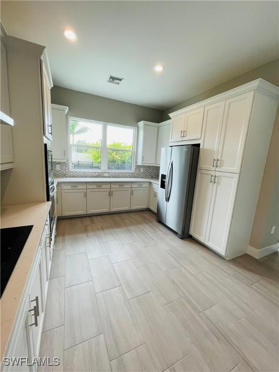 3608 Sapphire Cove Cir, Naples, FL 34114 - kitchen with recessed lighting, decorative backsplash, visible vents, white cabinetry, and appliances with stainless steel finishes