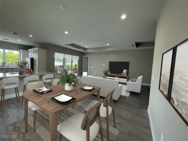 dining space with a healthy amount of sunlight, baseboards, a tray ceiling, and recessed lighting