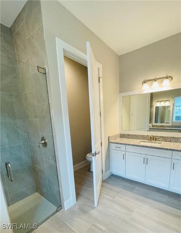 bathroom featuring vanity, a shower stall, toilet, and baseboards