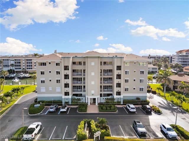 view of building exterior with uncovered parking and a water view