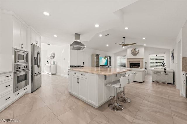 kitchen with lofted ceiling, extractor fan, white cabinetry, open floor plan, and appliances with stainless steel finishes