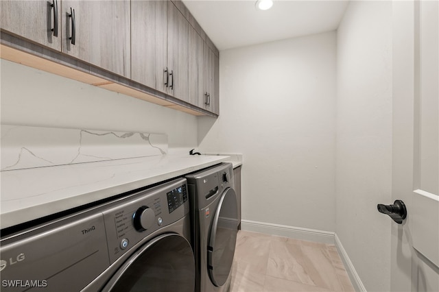 laundry area featuring washer and clothes dryer, cabinet space, and baseboards