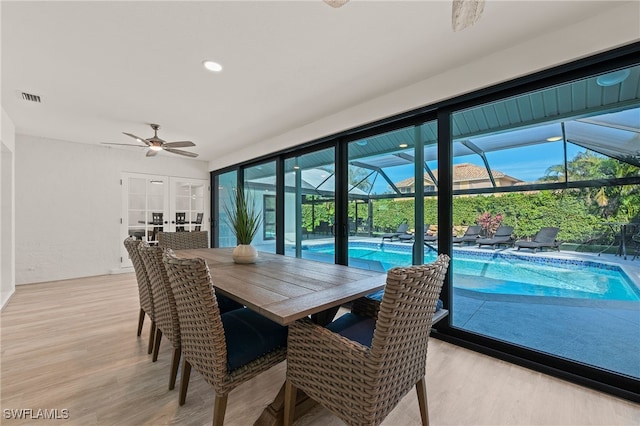 dining space featuring light wood-style floors, a sunroom, visible vents, and plenty of natural light