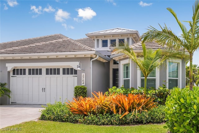 view of front of house with a tile roof, driveway, an attached garage, and stucco siding