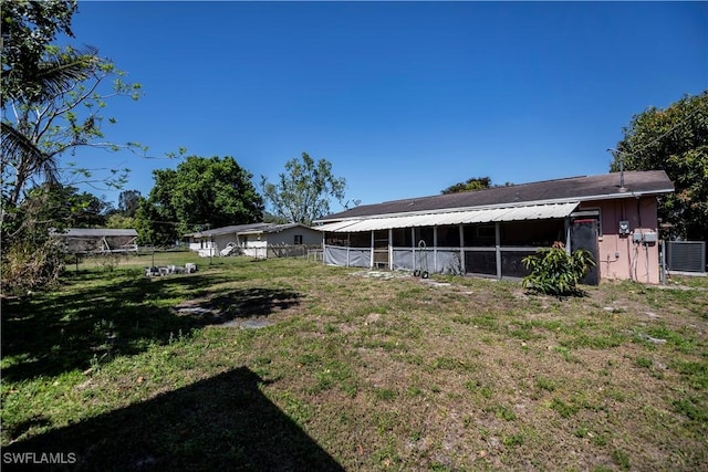 rear view of property featuring central AC unit, fence, and a lawn