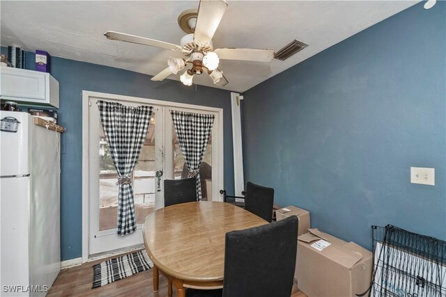 dining space featuring french doors, visible vents, a ceiling fan, wood finished floors, and baseboards