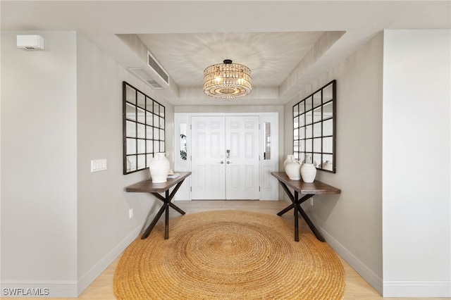 entrance foyer with an inviting chandelier, visible vents, baseboards, and light wood-style floors