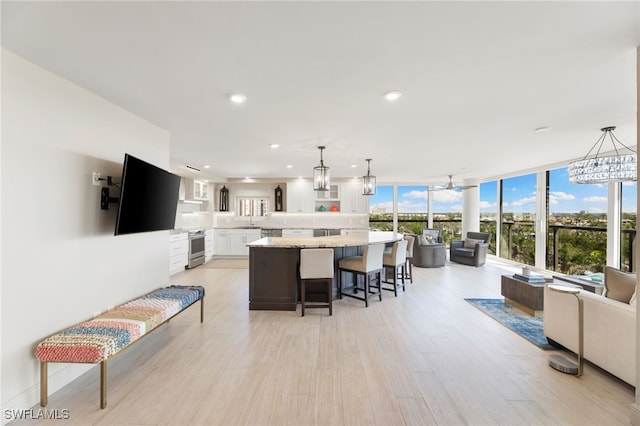 kitchen with stainless steel stove, a breakfast bar, a kitchen island, white cabinetry, and pendant lighting