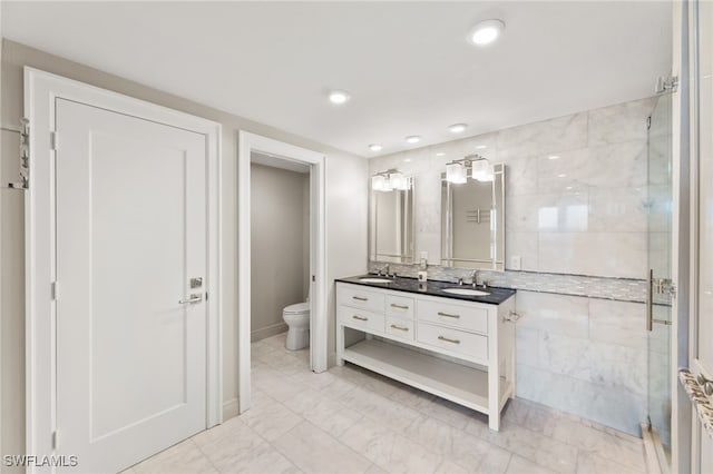 bathroom with double vanity, a stall shower, a sink, and toilet