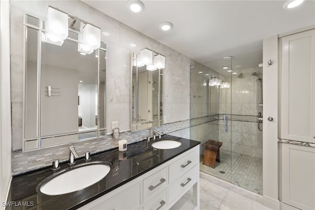 bathroom featuring double vanity, a stall shower, tasteful backsplash, and a sink