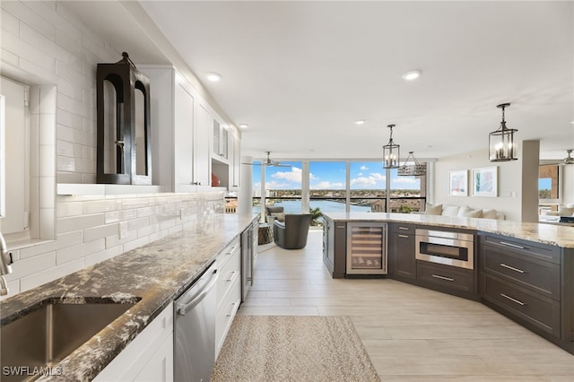 kitchen with beverage cooler, a sink, white cabinets, decorative backsplash, and dishwasher