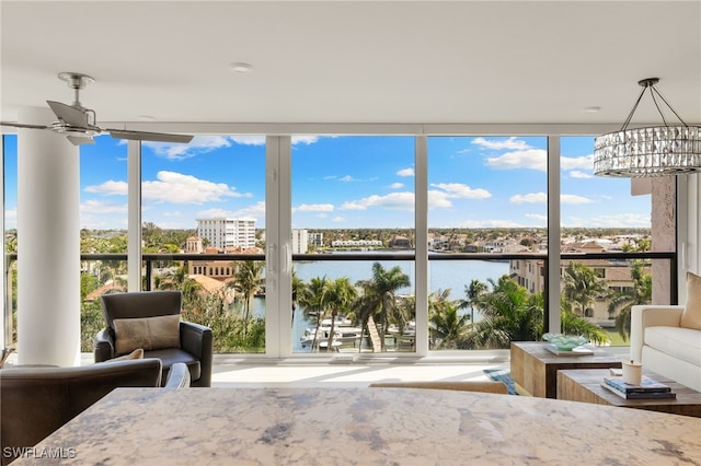 sunroom / solarium with a water view, plenty of natural light, and ceiling fan with notable chandelier