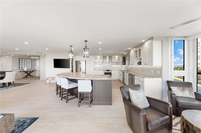 kitchen with white cabinets, glass insert cabinets, a sink, stainless steel appliances, and backsplash