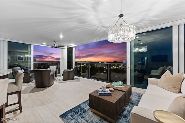 living area featuring ceiling fan with notable chandelier and expansive windows