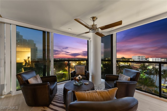 living area featuring ceiling fan, a wall of windows, a city view, and wood finished floors