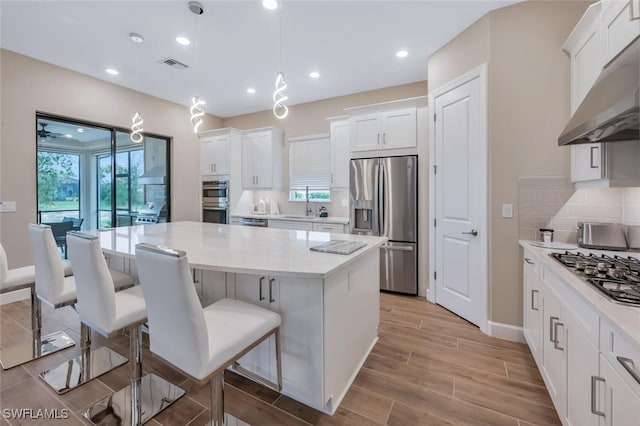 kitchen with visible vents, decorative backsplash, stainless steel appliances, under cabinet range hood, and white cabinetry