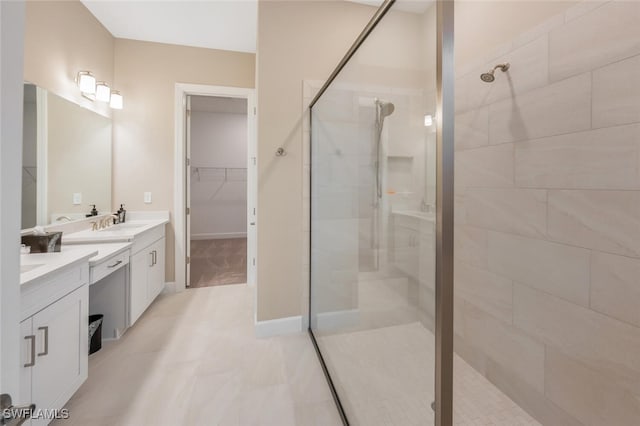 bathroom with a stall shower, a walk in closet, vanity, and baseboards