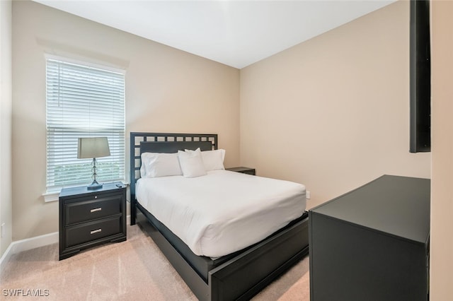 bedroom featuring light carpet and baseboards