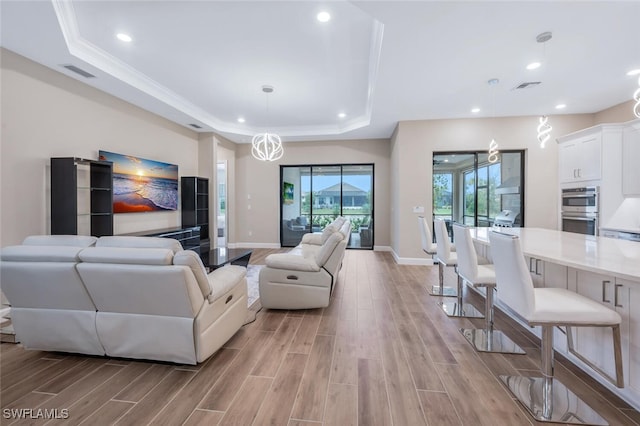 living room with wood tiled floor, visible vents, and a raised ceiling