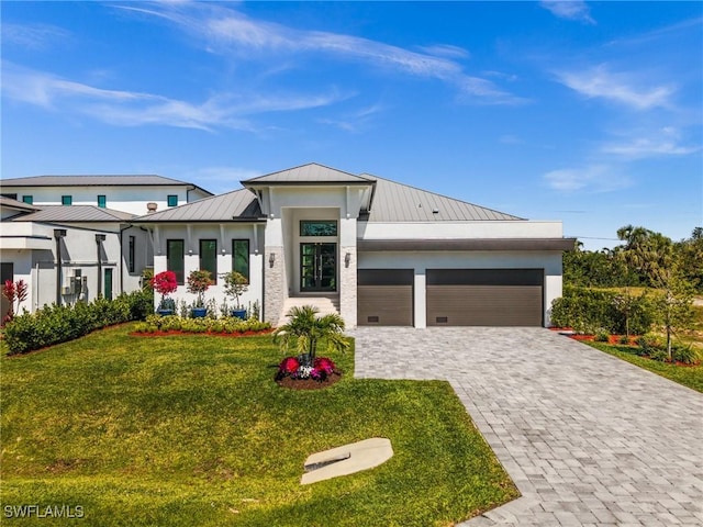 view of front of home with a front lawn, a standing seam roof, decorative driveway, an attached garage, and metal roof