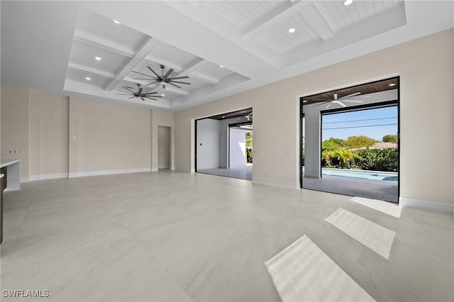 unfurnished living room with beam ceiling, a ceiling fan, and baseboards