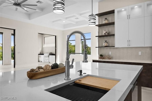 room details with open shelves, ceiling fan, light stone countertops, coffered ceiling, and a sink