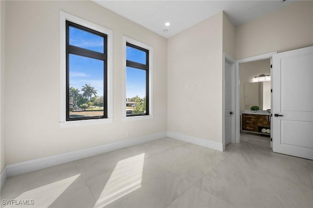 unfurnished bedroom with recessed lighting, baseboards, and ensuite bathroom