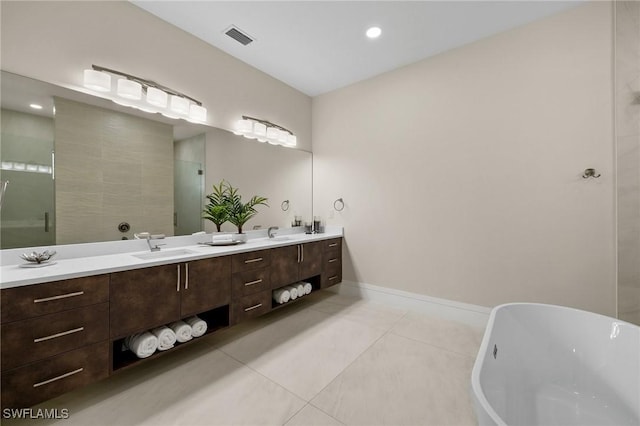 full bathroom with tile patterned flooring, visible vents, double vanity, a freestanding tub, and a sink