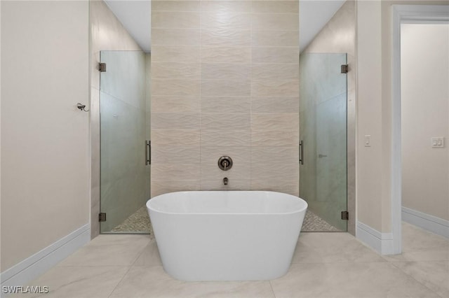bathroom with baseboards, a stall shower, a freestanding bath, tile patterned flooring, and tile walls