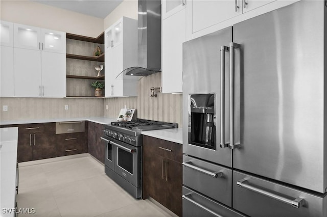 kitchen with dark brown cabinets, wall chimney range hood, white cabinetry, high end appliances, and open shelves