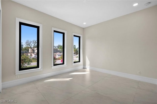 spare room with recessed lighting and baseboards