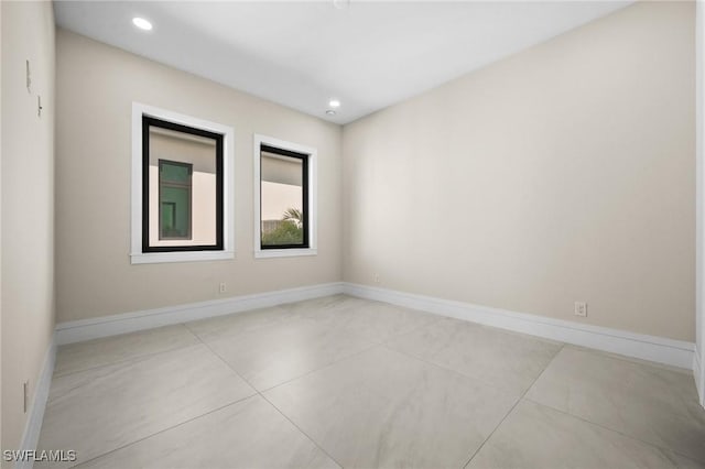 spare room with recessed lighting and baseboards