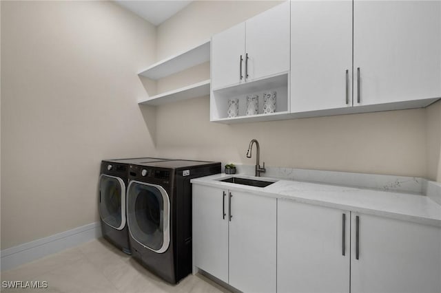 clothes washing area with baseboards, washer and clothes dryer, light tile patterned flooring, cabinet space, and a sink