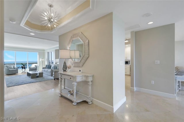 corridor with recessed lighting, baseboards, a raised ceiling, a notable chandelier, and light tile patterned flooring