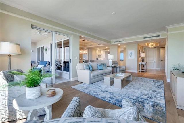 living room with baseboards, crown molding, visible vents, and wood finished floors