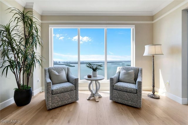 sitting room featuring a water view, crown molding, baseboards, and wood finished floors