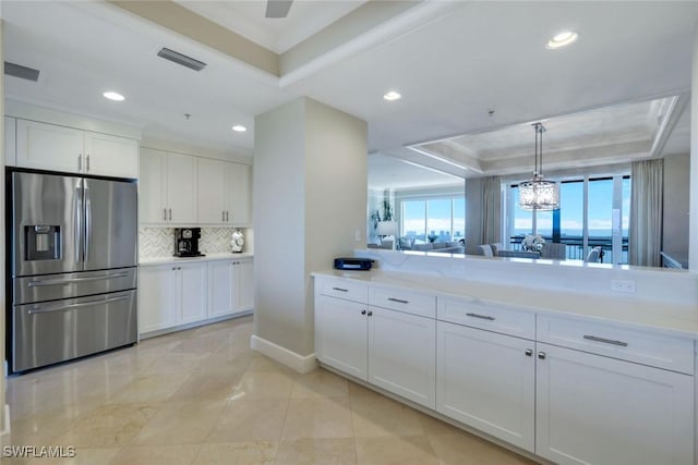 kitchen with a tray ceiling, crown molding, decorative backsplash, white cabinetry, and stainless steel fridge with ice dispenser