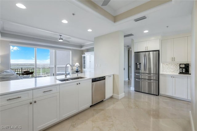 kitchen featuring stainless steel appliances, tasteful backsplash, a raised ceiling, a ceiling fan, and a sink