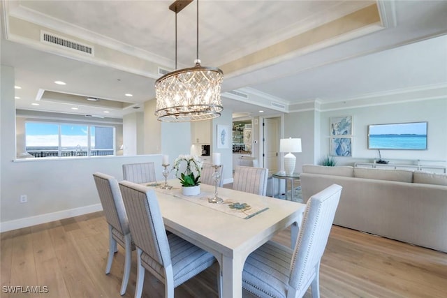 dining area with baseboards, visible vents, ornamental molding, wood finished floors, and a tray ceiling