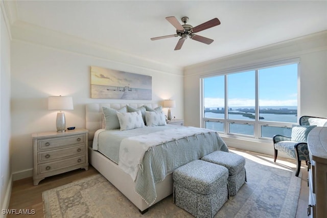 bedroom with a water view, light wood-style flooring, ceiling fan, and crown molding