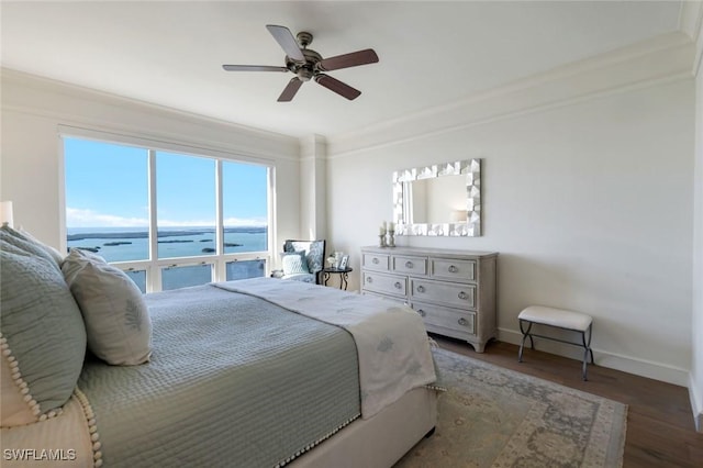 bedroom with a water view, wood finished floors, a ceiling fan, and baseboards