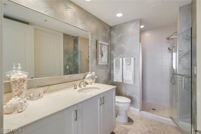 bathroom featuring toilet, visible vents, vanity, a stall shower, and wallpapered walls