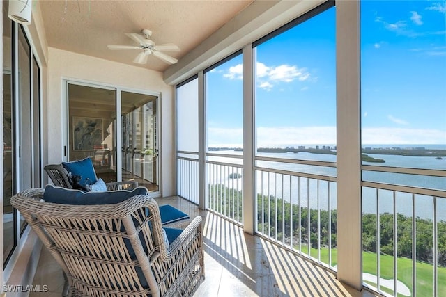 sunroom / solarium featuring a water view and ceiling fan