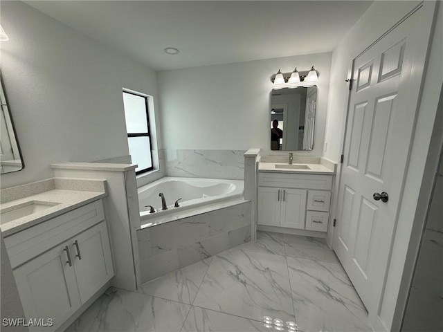 bathroom featuring a garden tub, marble finish floor, two vanities, and a sink