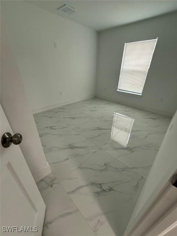 empty room featuring marble finish floor, visible vents, and baseboards