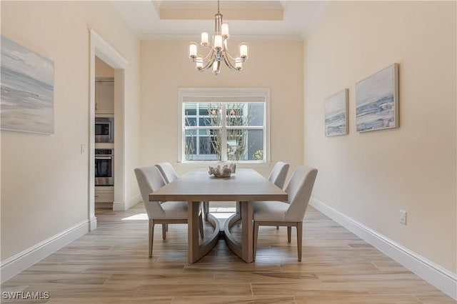 dining area featuring baseboards, a notable chandelier, a raised ceiling, and light wood-style floors